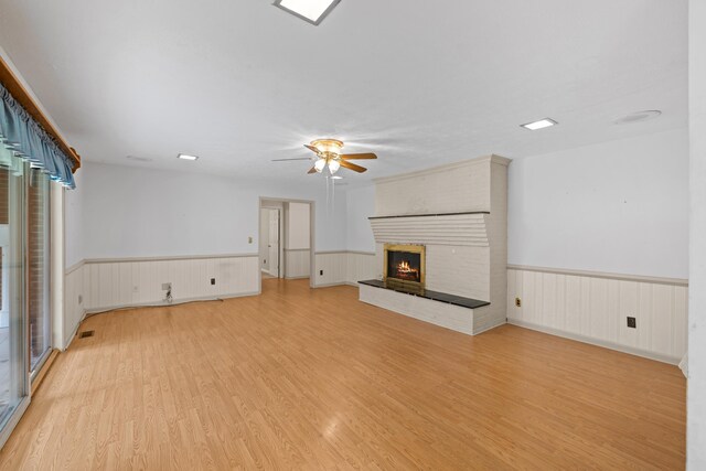 192 Sandy Ridge Rd, Waynesboro, VA 22801 - unfurnished living room featuring light wood-style floors, ceiling fan, a wainscoted wall, and a brick fireplace