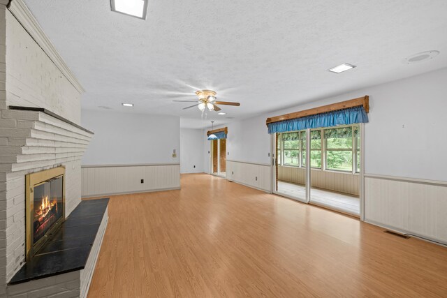 192 Sandy Ridge Rd, Waynesboro, VA 22801 - unfurnished living room featuring wainscoting, a ceiling fan, a brick fireplace, a textured ceiling, and wood finished floors
