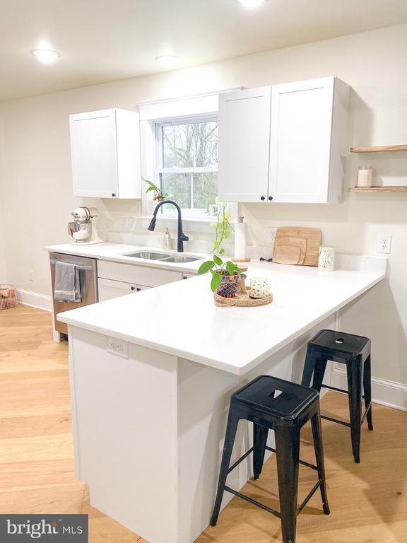 kitchen featuring sink, stainless steel dishwasher, a kitchen breakfast bar, and white cabinets