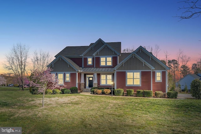 craftsman inspired home with board and batten siding, a standing seam roof, a front yard, and stone siding