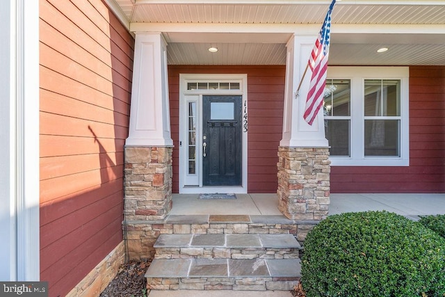 view of exterior entry featuring a porch and stone siding