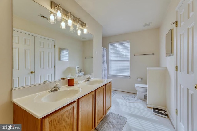 full bath featuring toilet, plenty of natural light, baseboards, and double vanity