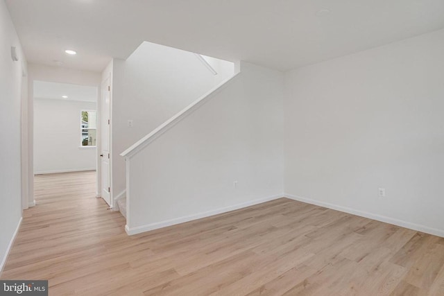 spare room featuring light wood finished floors, stairway, recessed lighting, and baseboards