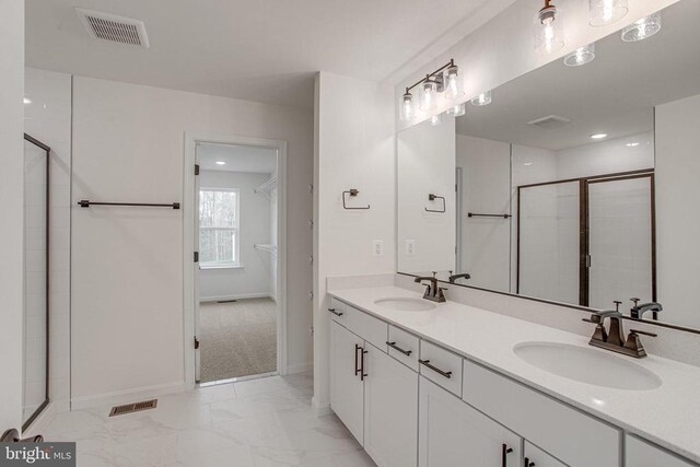 bathroom with a shower stall, marble finish floors, double vanity, and baseboards