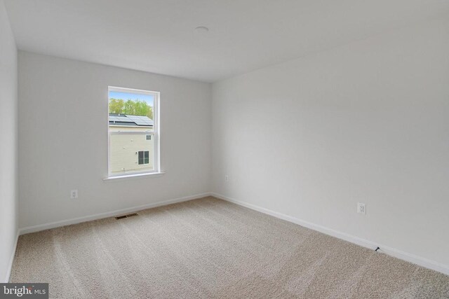 spare room featuring carpet and baseboards