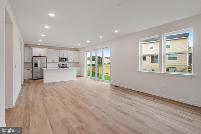 unfurnished living room with light wood-style flooring, recessed lighting, and baseboards