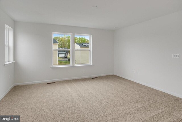 carpeted spare room featuring baseboards