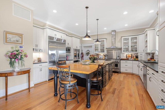 2055 Thomas Jefferson Pkwy, Charlottesville, VA 22902 - kitchen with built in appliances, visible vents, a sink, a kitchen breakfast bar, and wall chimney exhaust hood