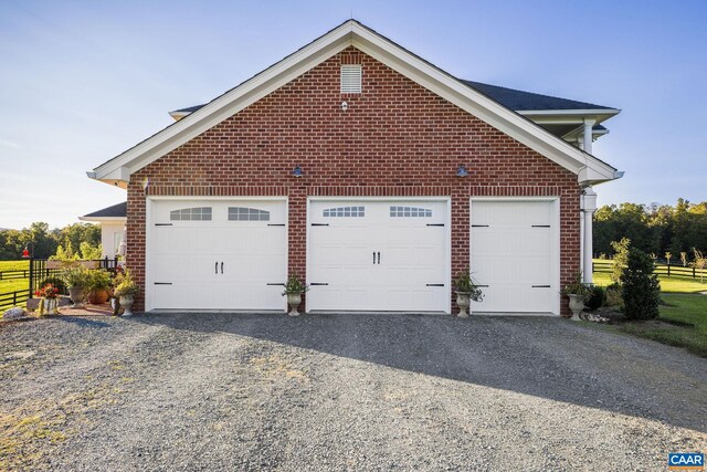 2055 Thomas Jefferson Pkwy, Charlottesville, VA 22902 - view of home's exterior with gravel driveway, brick siding, a garage, and fence
