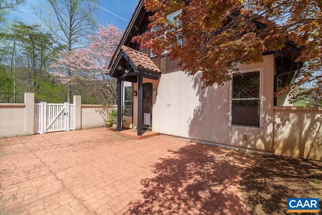 7035 Blackwells Hollow Rd, Crozet, VA 22932 - view of property exterior featuring a gate, fence, a patio area, stucco siding, and a tile roof