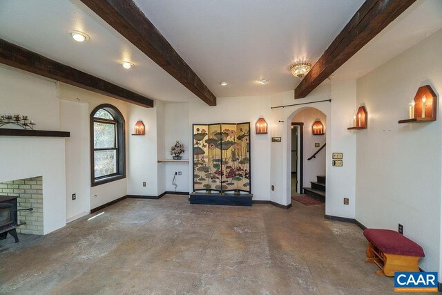 7035 Blackwells Hollow Rd, Crozet, VA 22932 - unfurnished living room featuring beamed ceiling, concrete floors, baseboards, stairs, and arched walkways