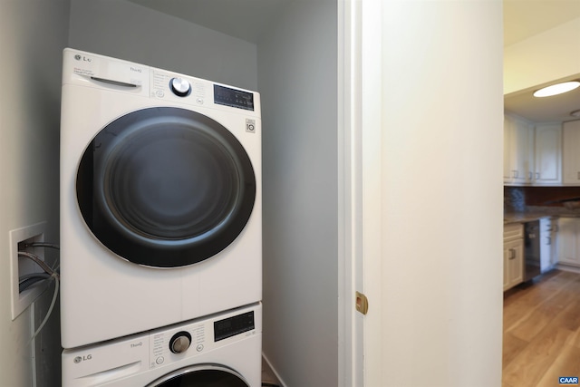 laundry area featuring stacked washing maching and dryer and light wood-style flooring