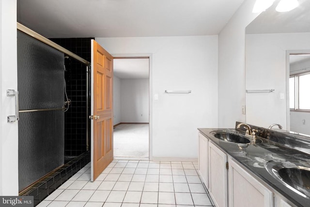 bathroom with tile patterned floors, a shower stall, double vanity, and baseboards