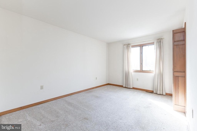 spare room with light colored carpet and baseboards