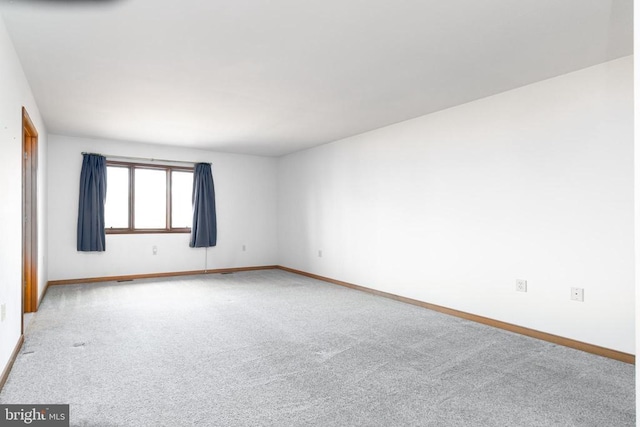 spare room featuring carpet flooring and baseboards