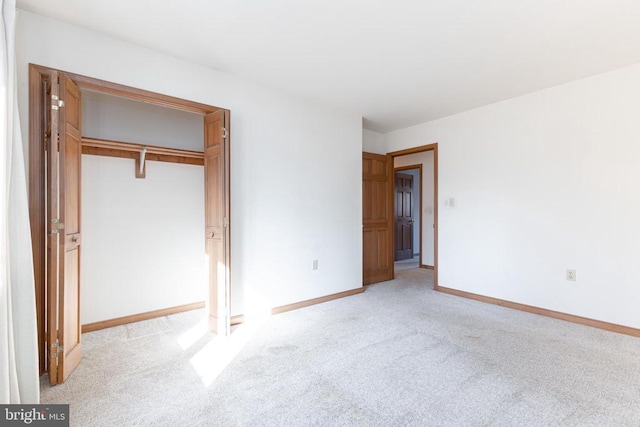 unfurnished bedroom with light colored carpet, baseboards, and a closet