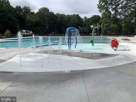 community pool with a water play area and a view of trees