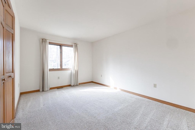 unfurnished room with light colored carpet and baseboards