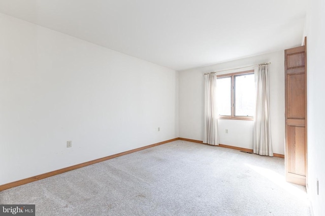 unfurnished room featuring light carpet and baseboards