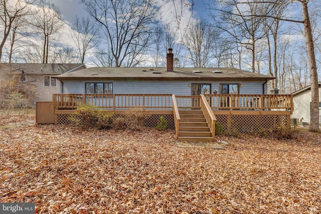 rear view of house featuring a chimney, a wooden deck, and stairway