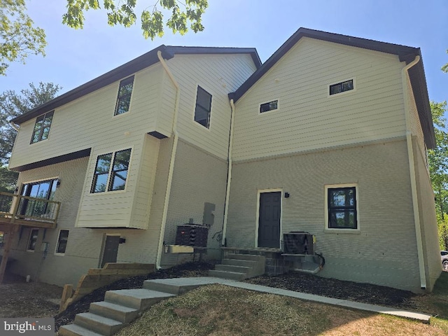 back of house with central AC unit and brick siding