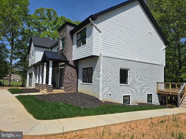 view of side of property featuring a deck and brick siding