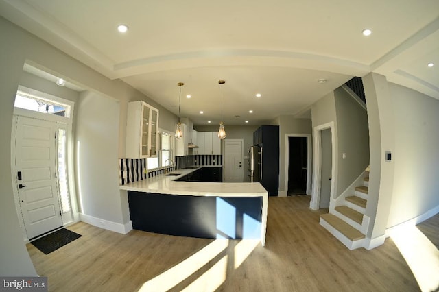 kitchen featuring freestanding refrigerator, light wood-style floors, light countertops, and glass insert cabinets