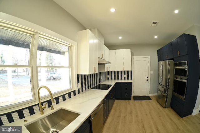 kitchen featuring a sink, stainless steel appliances, visible vents, under cabinet range hood, and light wood-style floors