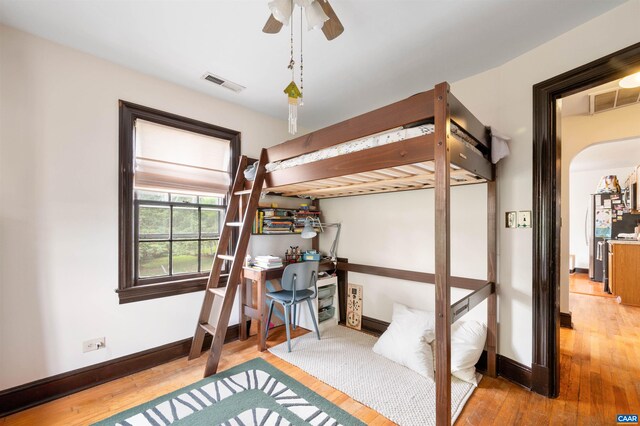 bedroom with hardwood / wood-style floors, baseboards, and arched walkways