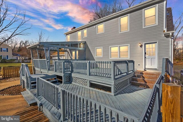 back house at dusk featuring a wooden deck