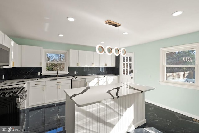 kitchen featuring tasteful backsplash, white cabinets, marble finish floor, stainless steel appliances, and a sink