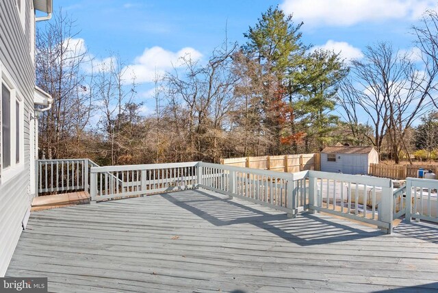 deck with an outdoor structure, a fenced backyard, and a shed