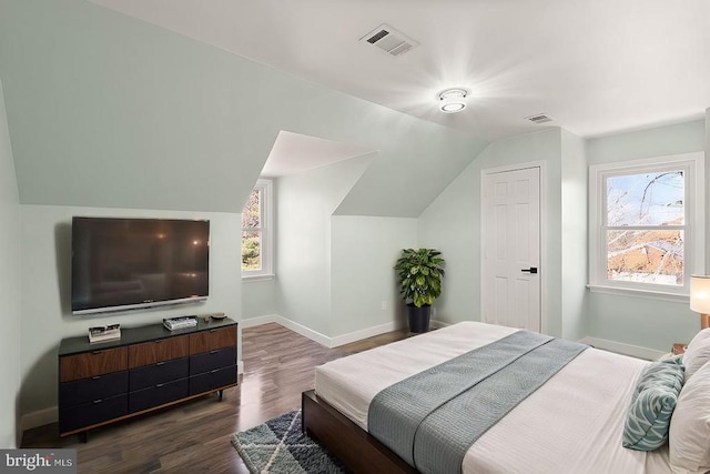 bedroom featuring dark wood finished floors, visible vents, baseboards, and vaulted ceiling