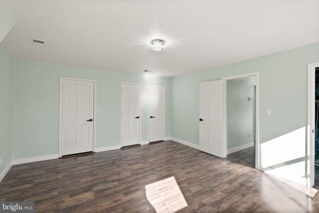 unfurnished bedroom featuring dark wood finished floors, visible vents, and baseboards