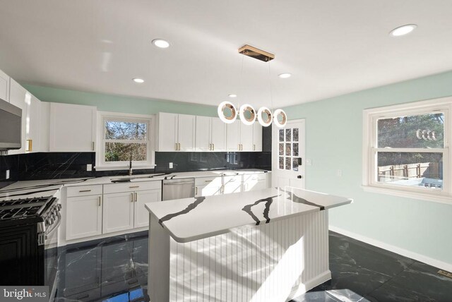 kitchen featuring tasteful backsplash, appliances with stainless steel finishes, marble finish floor, white cabinetry, and a sink