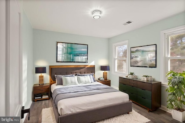 bedroom featuring visible vents, multiple windows, baseboards, and wood finished floors