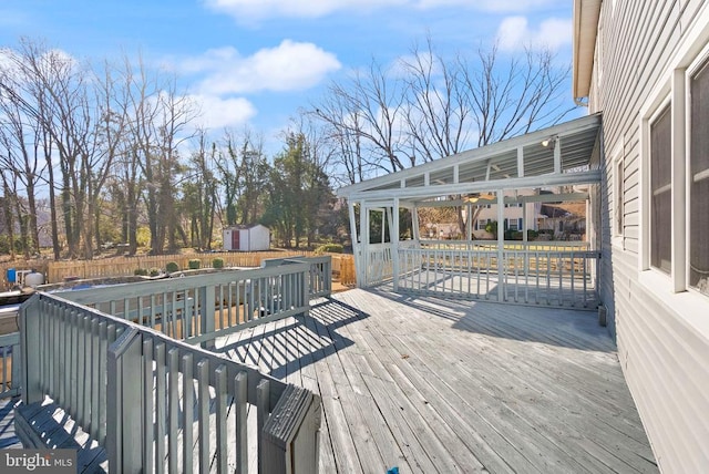 wooden terrace featuring a storage shed, an outbuilding, and fence