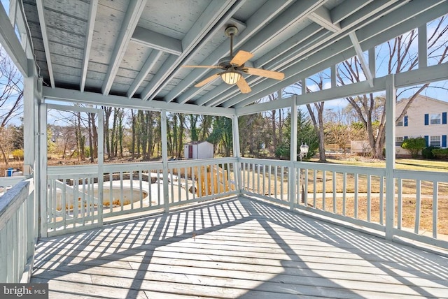 deck featuring an outdoor structure, a ceiling fan, and a shed