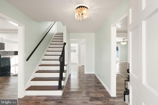 entrance foyer featuring an inviting chandelier, stairway, wood finished floors, and baseboards