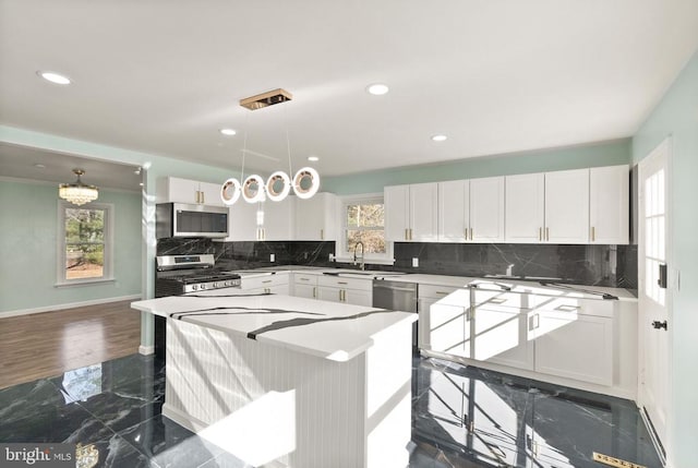 kitchen with marble finish floor, appliances with stainless steel finishes, white cabinetry, and a sink