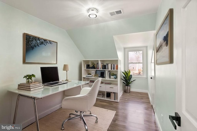 office featuring visible vents, lofted ceiling, baseboards, and wood finished floors