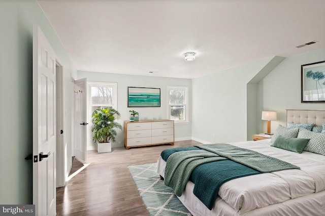 bedroom with wood finished floors, visible vents, and baseboards