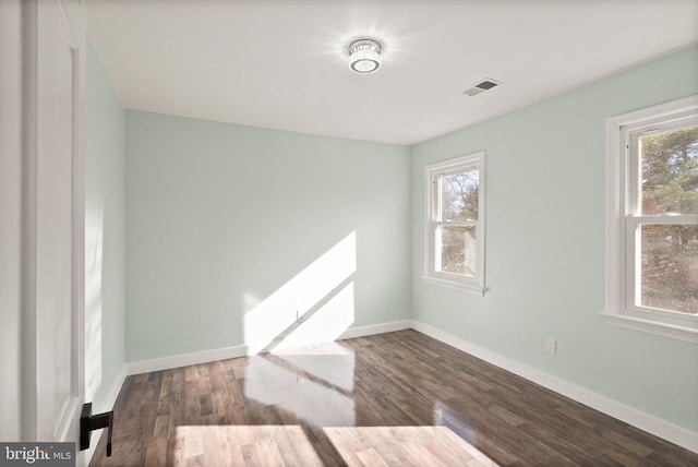 unfurnished room with plenty of natural light, baseboards, visible vents, and wood finished floors