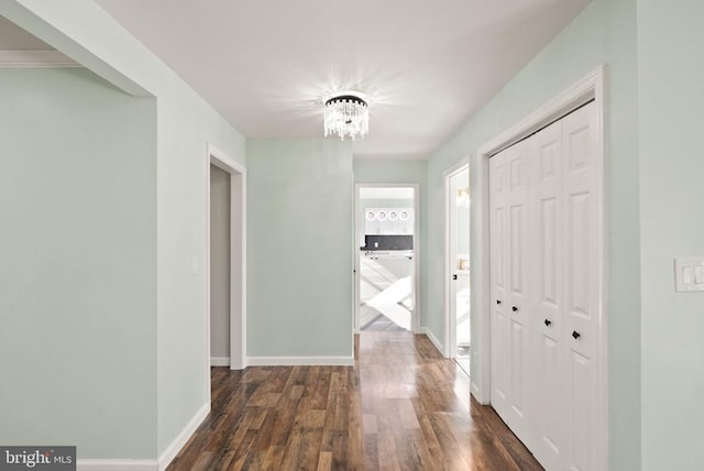 hallway with a notable chandelier, baseboards, and dark wood-type flooring