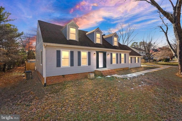 view of front of home with central AC unit and a yard