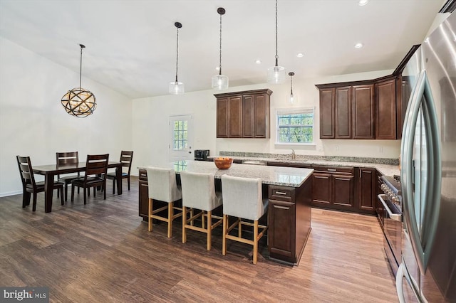  - kitchen with appliances with stainless steel finishes, a center island, dark brown cabinetry, wood finished floors, and recessed lighting