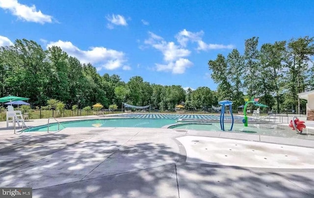 community pool featuring fence, a patio, and view of scattered trees