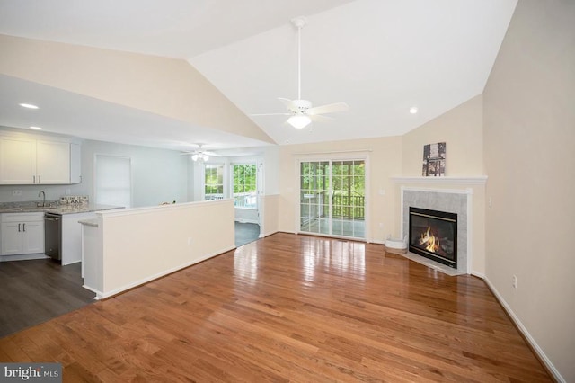 unfurnished living room with lofted ceiling, ceiling fan, a sink, wood finished floors, and a premium fireplace