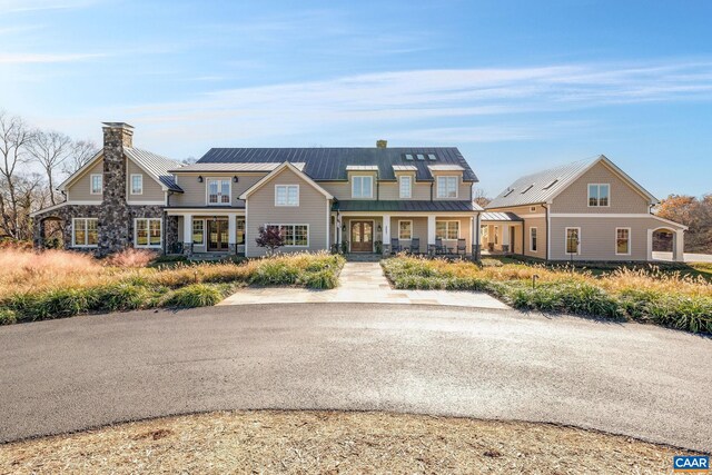 craftsman inspired home featuring a chimney, a standing seam roof, metal roof, covered porch, and stone siding