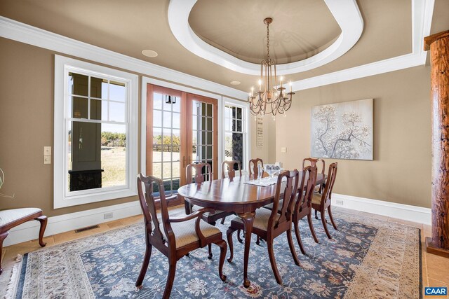 dining space with a notable chandelier, baseboards, ornamental molding, visible vents, and a raised ceiling